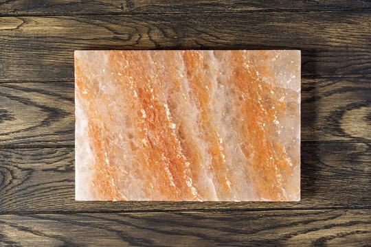 Pink himalayan salt block for cooking and serving the dish on oak wooden table with copy space