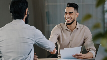Two successful diverse business men colleague arabian salesman banker male manager shaking hand...