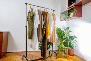 Second-hand clothes  on the rail at home. The concept of sustainable economic life
