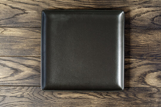 Empty rectangular black plate on oak wooden background. Top view, with copy space
