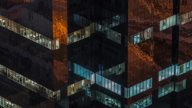 Windows in office building exterior in the late night with interior lights on timelapse