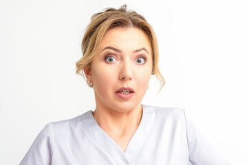 Female doctor shocked. Close up portrait of a young caucasian woman looking surprised with wide eyes stared isolated white wall background