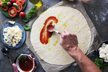 Chefs hands preparing making pizza at kitchen. fresh home recepie. mozzarella ,basil ,tomatoe ,gorgonzola