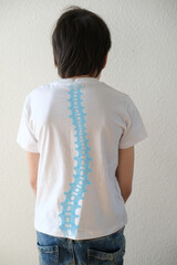 part of naked back of boy, child 10 years old in a white t-shirt bent over from back pain, concept of therapeutic massage for osteochondrosis, scoliosis, back pain, intervertebral hernia