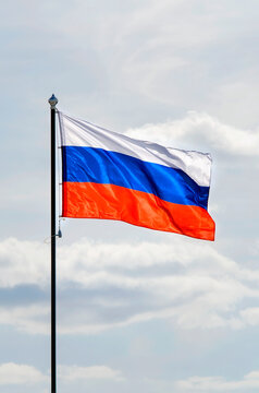 The Russian flag flutters in the wind against a blue sky. Vertical photography.