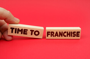 On a red background, wooden blocks, one of them in hand. The blocks are written - Time to Franchise