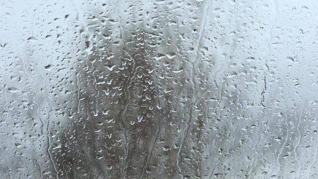 Close-up of water drops on the glass, Rain, Go away. Large raindrops hit the window pane in early spring.