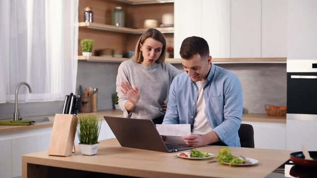 Misunderstood with documents. Young couple is on the kitchen at home at daytime together