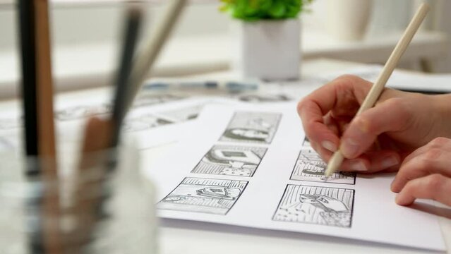 An artist draws cartoon characters storyboard frames. Sketches of comics on sheets of paper.