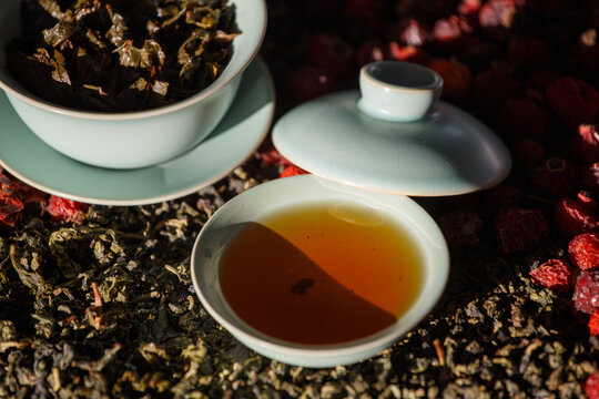 Gaivan and bowls with green tea and tea leaves on a brown background close-up,selective focus. Tea ceremony. Traditional Chinese tea ware.Gaiwan cup.Zhu yao ceramic.Chinese ceramics.Blurred defocused.