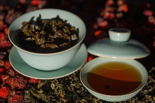Gaivan and bowls with green tea and tea leaves on a brown background close-up, selective focus. Tea ceremony. Traditional Chinese tea ware. Gaiwan cup. Zhu yao ceramic. Chinese ceramics. Relax. 