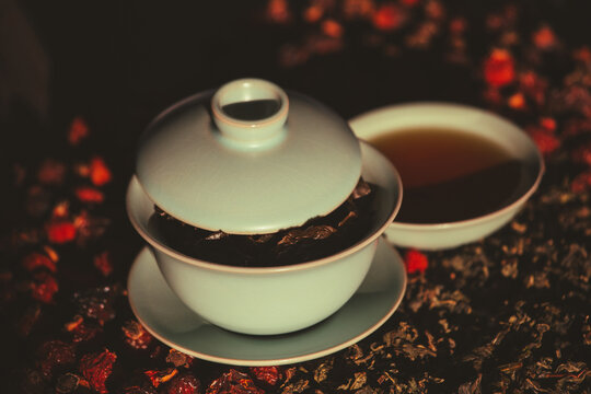 Gaivan and bowls with green tea and tea leaves on a brown background close-up, selective focus. Tea ceremony. Traditional Chinese tea ware. Gaiwan cup. Zhu yao ceramic. Chinese ceramics. Relax. 