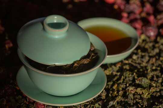 Gaivan and bowls with green tea and tea leaves on a brown background close-up, selective focus. Tea ceremony. Traditional Chinese tea ware. Gaiwan cup. Zhu yao ceramic. Chinese ceramics. Relax. 
