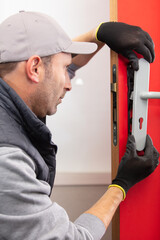 locksmith with gloves installing door lock - obrazy, fototapety, plakaty
