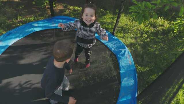 two children have fun jumping on a trampoline top view