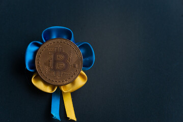 Bitcoin on a black background with the Ukrainian ensign. Concept