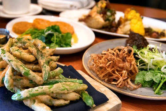 Grouping Of Various Appetizers, Including Fried Beans, Salad, And Onion Strings