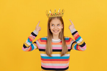 happy teen kid point finger on queen crown on yellow background