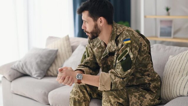 A soldier in Ukrainian uniform is sitting on the sofa and talking. Psychotherapy session