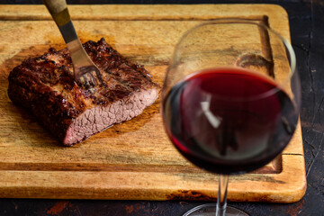 Roasted beef ribs with a glass of red wine presented on the table, traditional Argentine cuisine,...