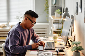 Portrait of Asian male creator retouching photographs at home office workplace and using pen tablet