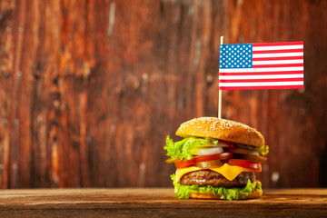 Close-up home made beef burger with american flag on the top on wooden table over old wooden...