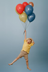 A funny kid in shorts and a straw hat is flying with colorful balloons on an isolated white background