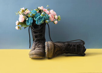 Military dirty combat boots with flowers on a yellow blue background conflict in Ukraine
