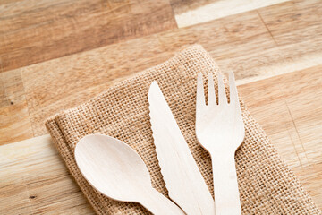 Eco-friendly, disposable, recyclable wooden cutlery placed on top of linen cloth and cutting board,...