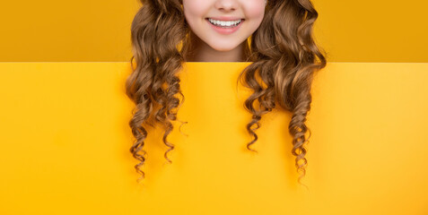 cheerful child behind blank yellow paper with copy space for advertisement