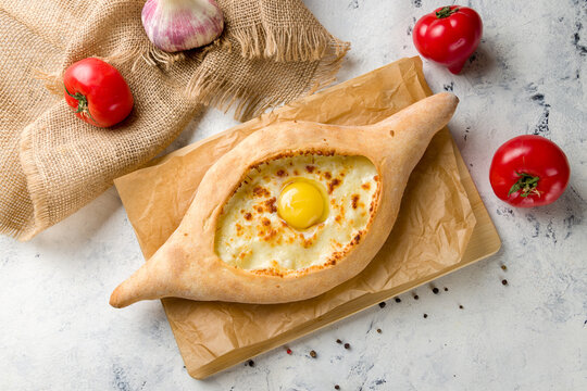 ajara Khachapuri with cheese, egg and butter, georgian kitchen on white concrete table top view