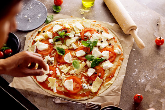 Chefs hands preparing making pizza at kitchen. fresh home recepie. mozzarella ,basil ,tomatoe ,gorgonzola