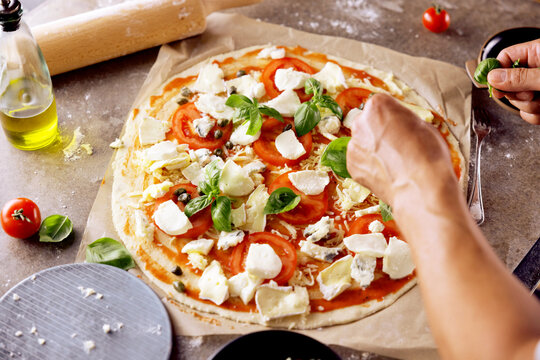 Chefs hands preparing making pizza at kitchen. fresh home recepie. mozzarella ,basil ,tomatoe ,gorgonzola