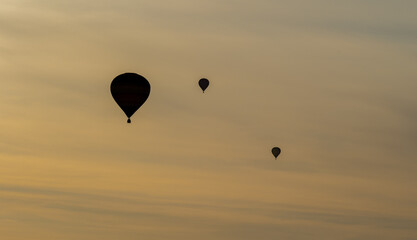 A group of hot air balloons flying over the River Exe as seen from Lympstone village, Devon, UK