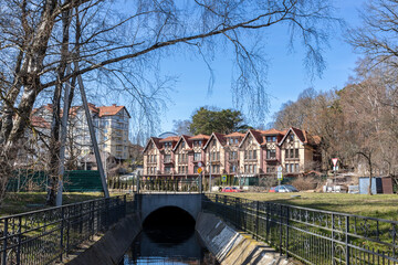 View of the Swiss-style houses from the side of the water channel and trees in Svetlogorsk Raushen, Kalinigrad region, Russia, near the Baltic sea in spring. 