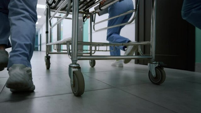 Doctors feet running down hospital corridor. Medical team moving gurney.