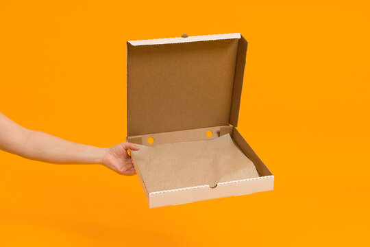 open empty pizza box in hand on color background