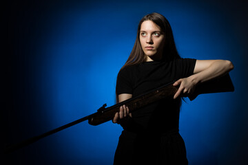 a young girl with long flowing hair in a black T-shirt with a gun in her hands on a dark background