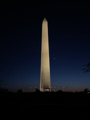 The Washington Monument at night with the moon shot from the National Mall.