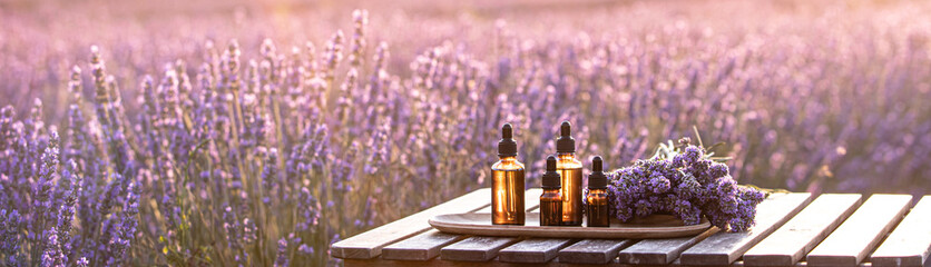 Amber essential lavender oil bottle. Violet lavendar field in Provence. - obrazy, fototapety, plakaty