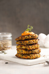 Vegetable carrot and quinoa pancakes in stack topped with paprika hummus, sunflower seeds. Healthy vegetarian food - plant based diet concept.