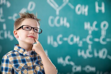 Education concept. Smart boy in glasses standing at the blackboard with formulas