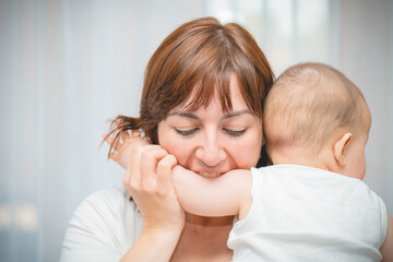 Young mother holding her newborn son. Woman and newborn child in white bedroom. Nursery interior. Mother playing with child. family at home. High quality photo