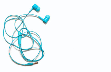 Tangled headphones lie on a white background. Blue headphones are twisted and untangling them is a...