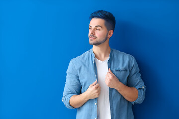 Stylish young man with unusual blue hair and beard on color background