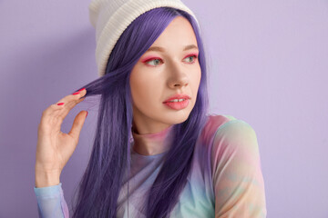 Gorgeous young woman with long violet hair on lilac background