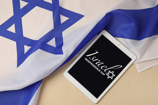 Tablet computer with text ISRAEL INDEPENDENCE DAY on screen and flag on light background