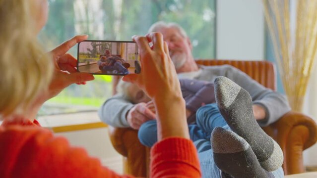 Grandmother with mobile phone taking picture of grandfather and granddaughter having daytime sleep at home together - shot in slow motion