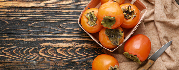 Ripe persimmons on wooden background with space for text