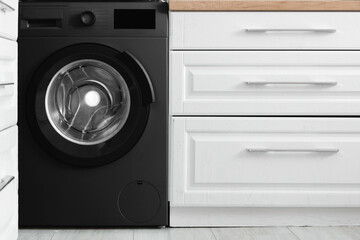 Modern black washing machine in kitchen